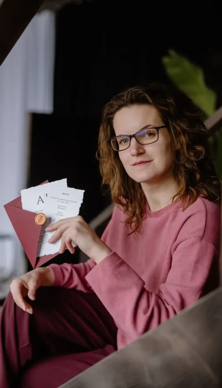 Aneta Różycka, trzymająca zaproszenie w ręce i siedząca na schodach