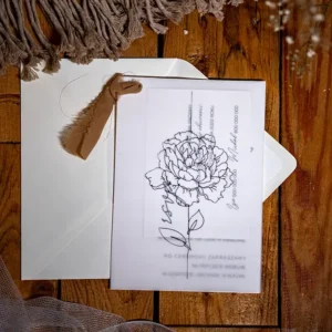 Białą koperta i białe zaproszenie z peonią